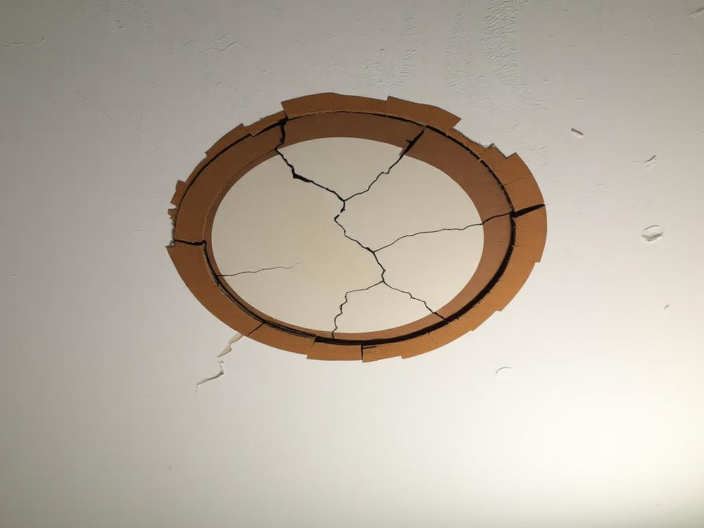 Damaged ceiling with water stain and cracked plaster